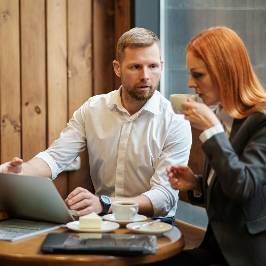 un consultant en marketing digital et sa cliente sont entrain de discuter la stratégie digitale de la prochaine campagne annuelle, en buvant un café